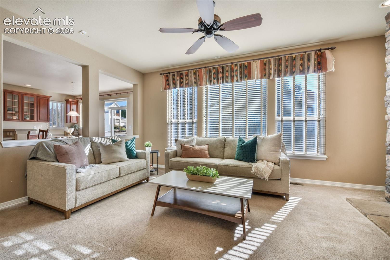 Recessed lighting, ceiling fan with wood-finish blades, and large windows with blinds
