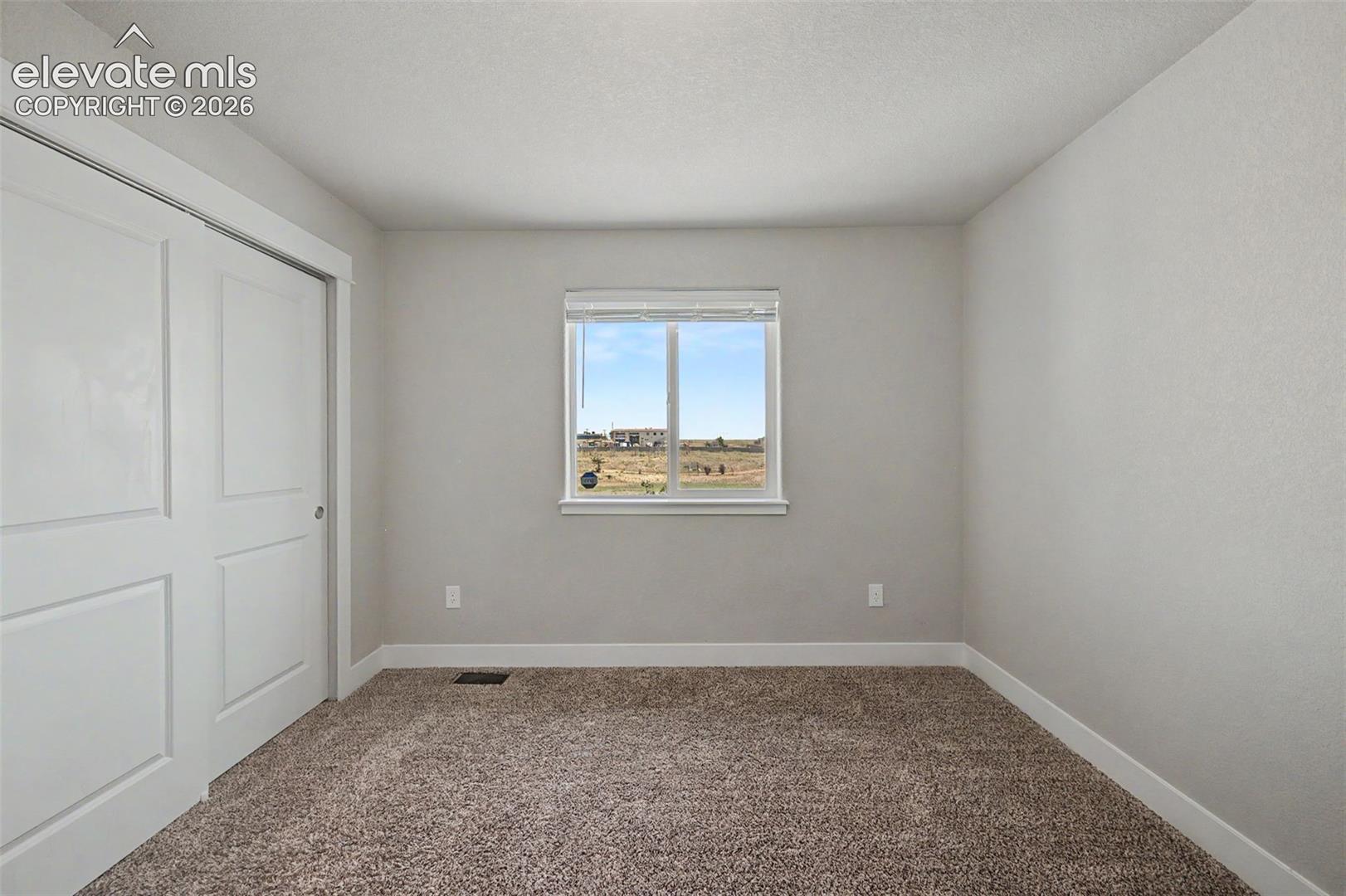 Neutral wall paint, brown textured carpet, and white baseboards