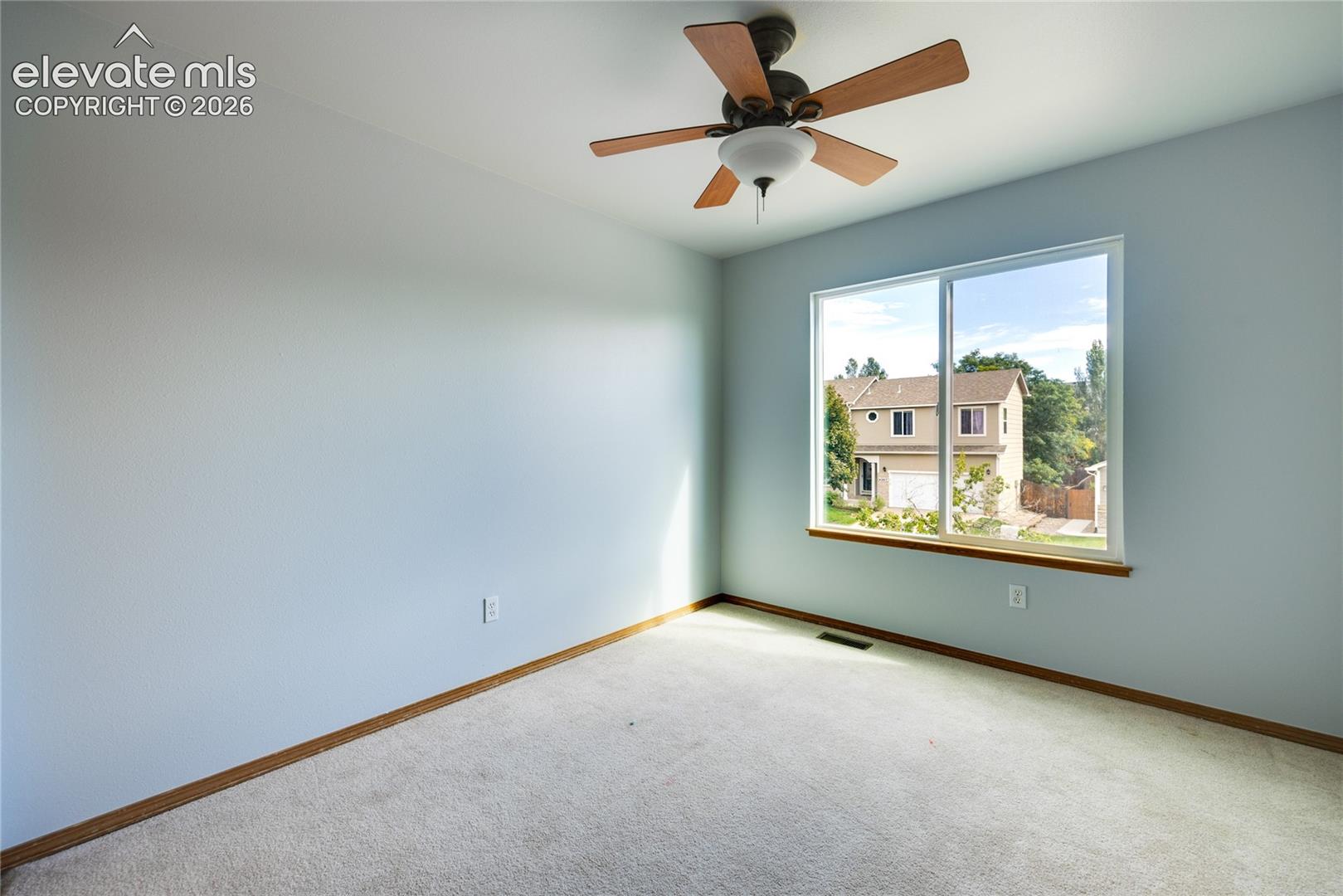 Wall-to-wall carpeting, wood-finish ceiling fan with integrated lighting, and a large window with wood-finish trim