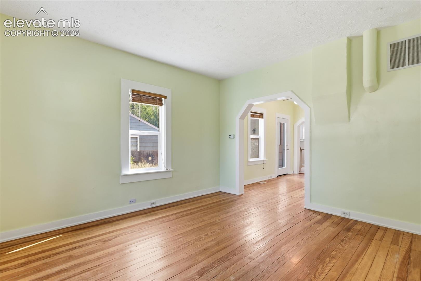 Living room with pine hardwood flooring throughout, arched opening, and white trim.
