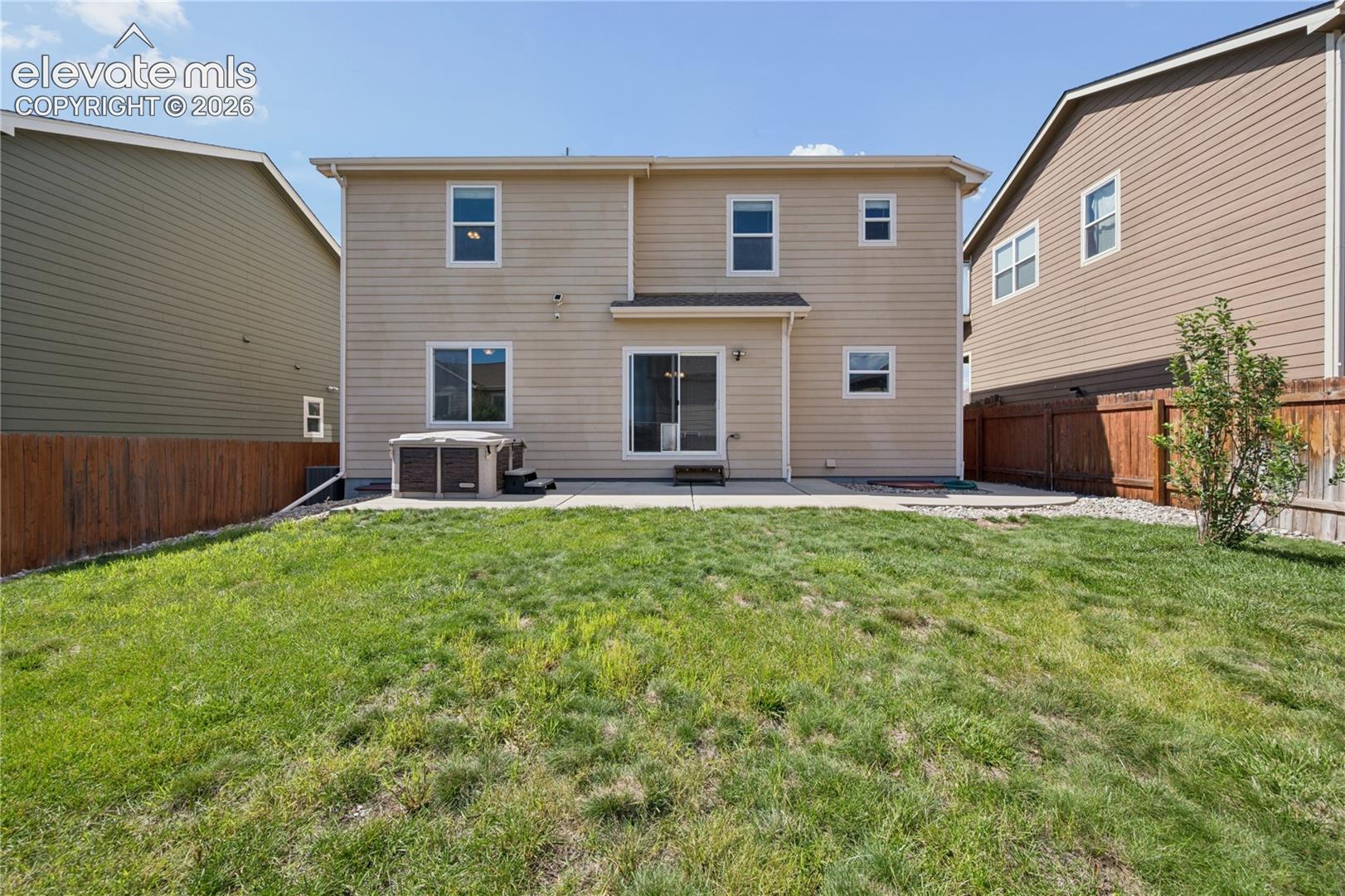 Fenced backyard, and a hot tub, green grass