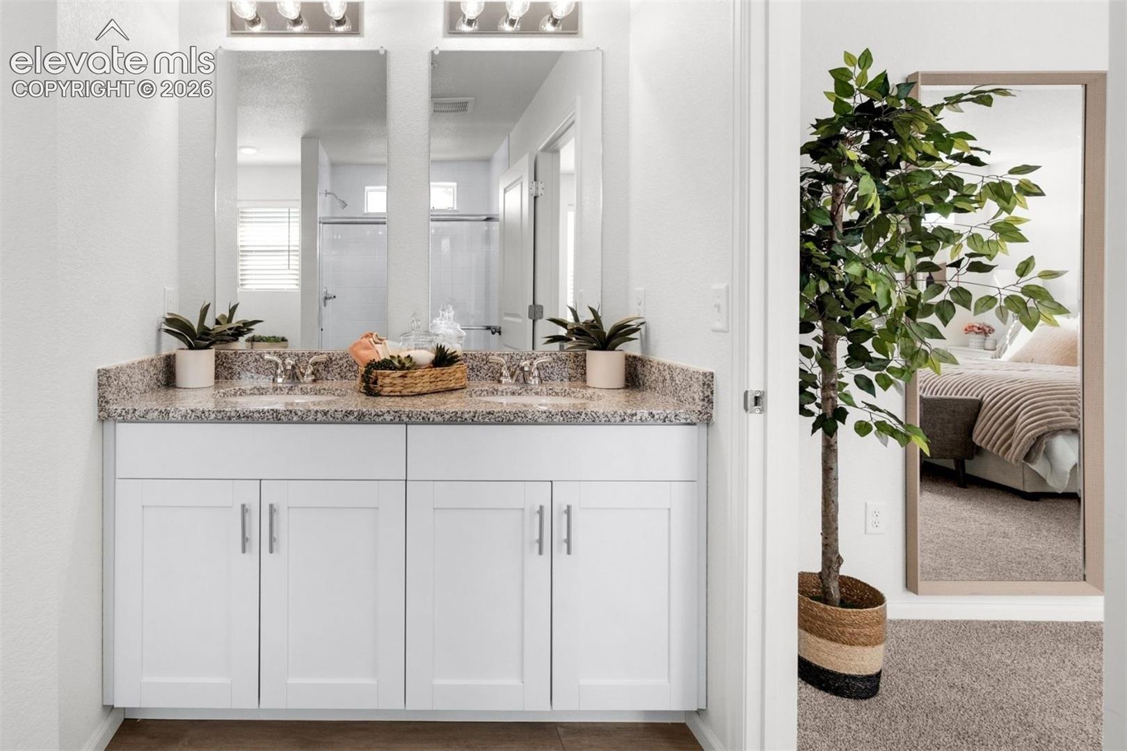 Dual vanity with granite countertop, individual sinks, and white shaker-style cabinetry
*photos of a model home*