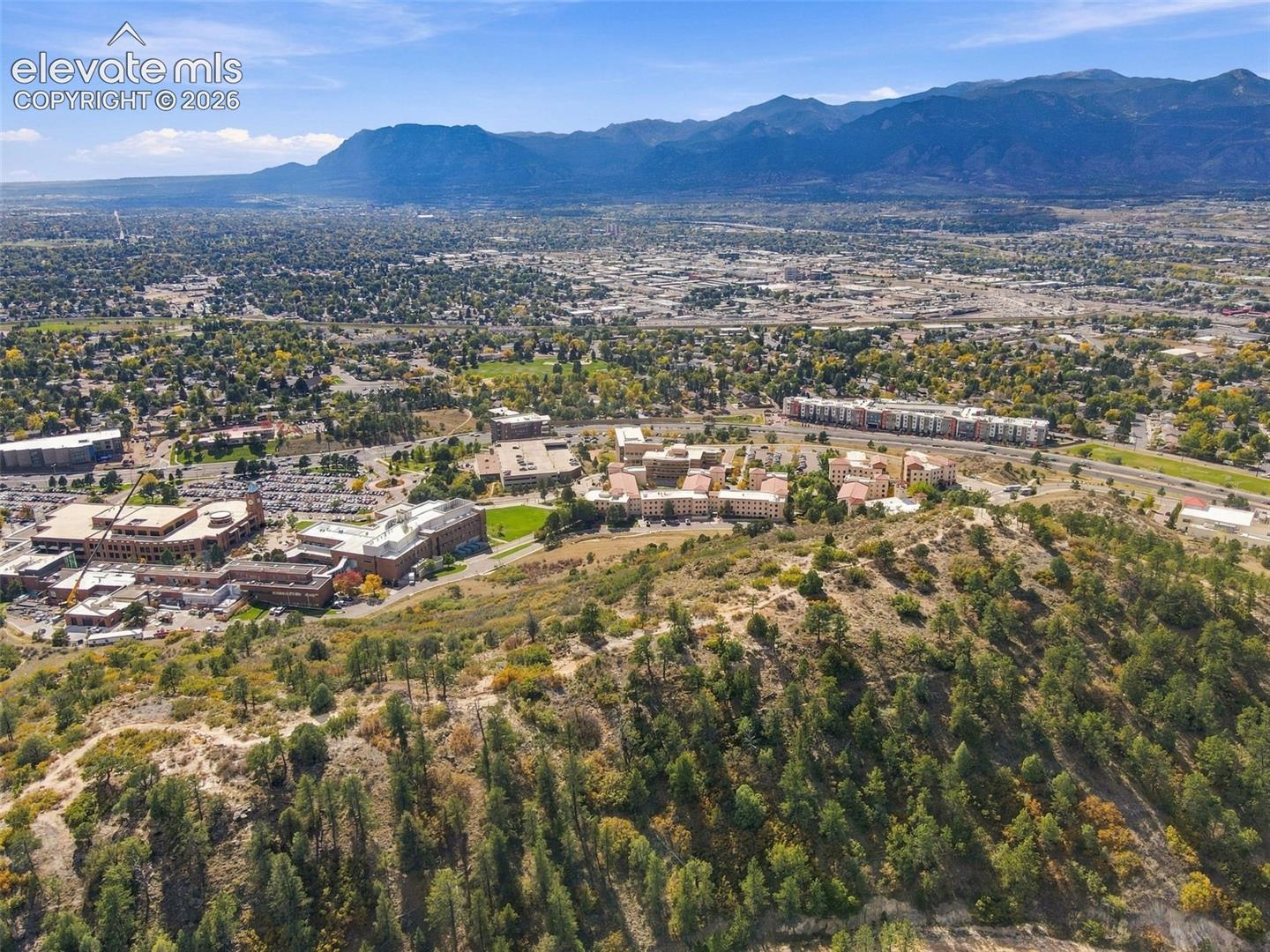 Aerial perspective featuring prominent mountain range, native evergreen vegetation, and established regional terrain