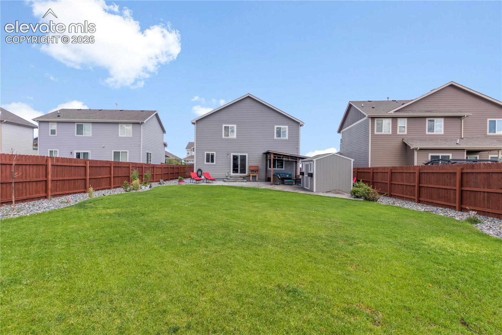 Expansive backyard with a manicured lawn, wood privacy fencing, and a gravel border