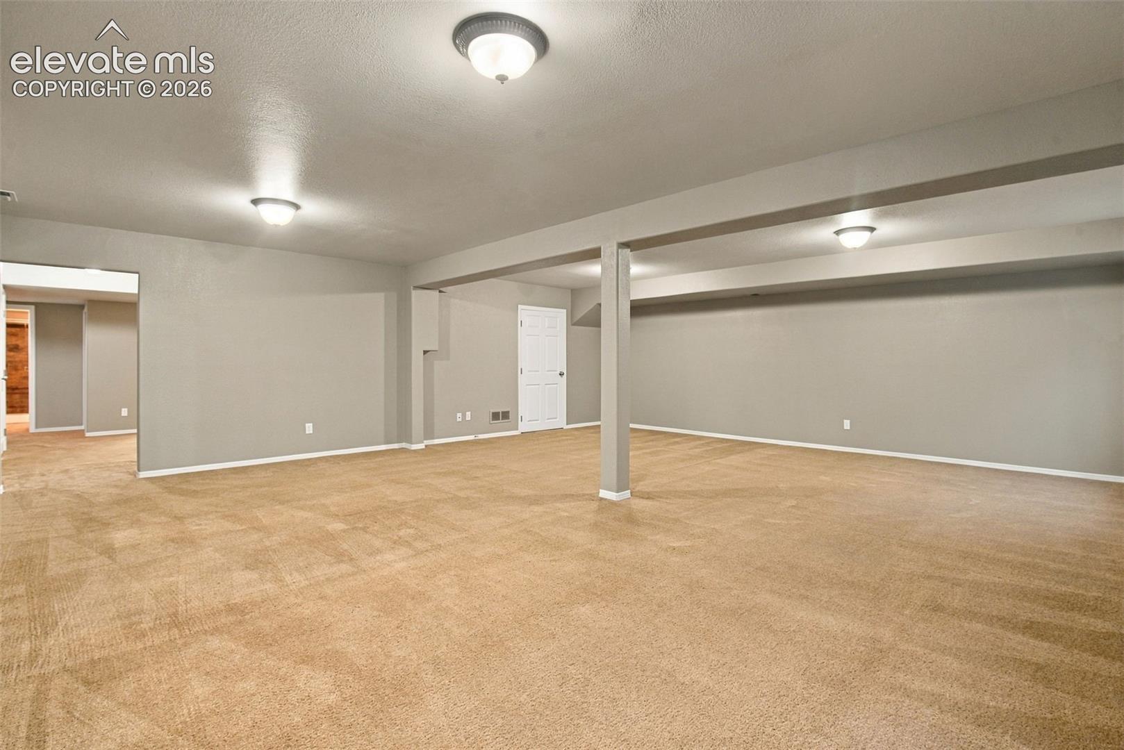 Expansive carpeted area with neutral wall paint, recessed lighting, and white trim