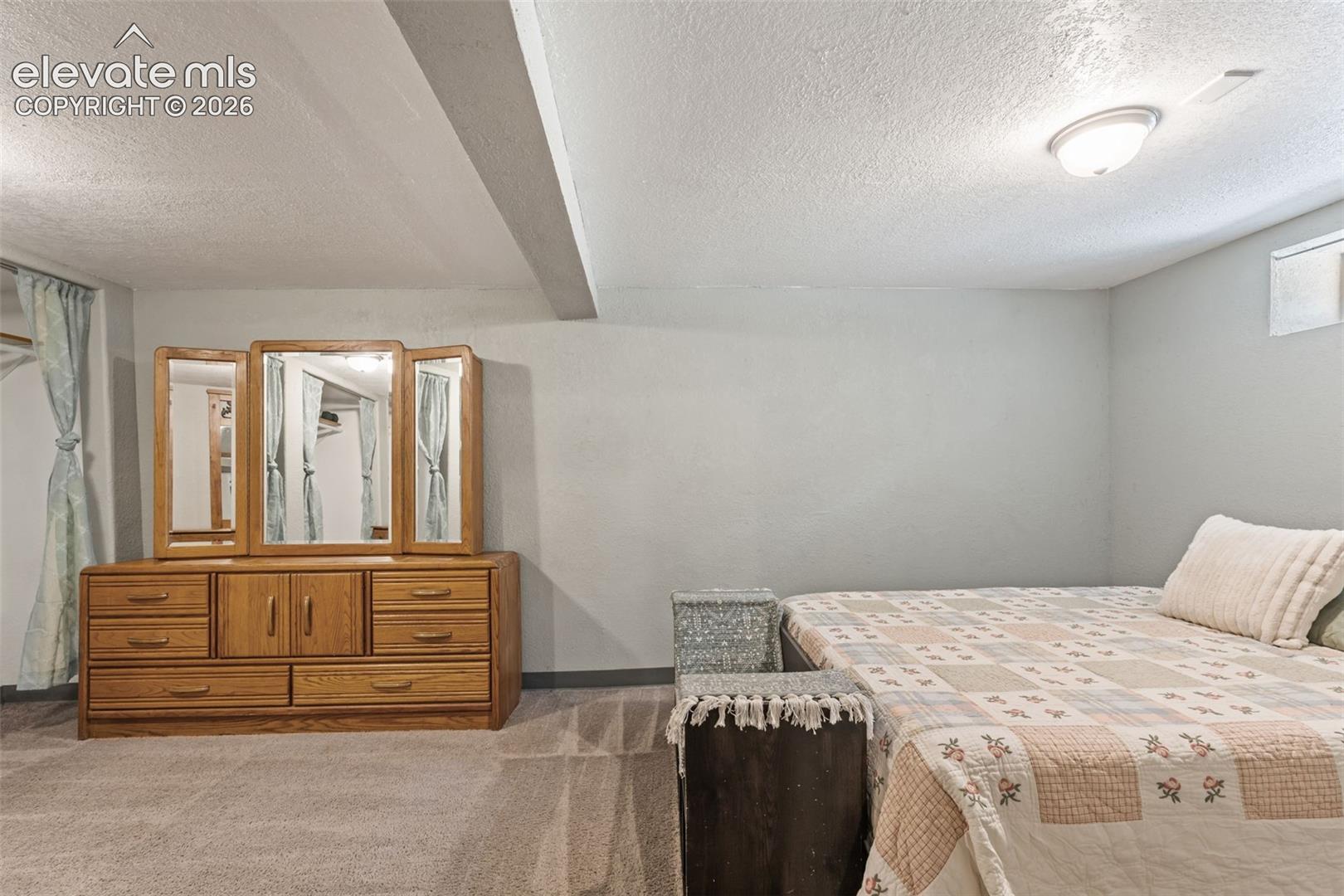 Recessed ceiling beam with flush-mounted lighting, textured ceiling, light gray wall finishes, and wall-to-wall carpeting