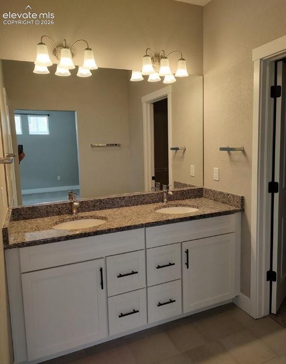 Dual-sink vanity featuring white cabinetry, stone-finish countertops, matte black hardware, and double wall-mounted light fixtures