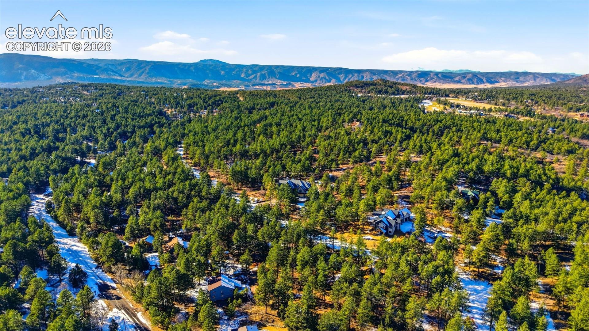 Expansive treed landscape with scattered residences and distant mountain ranges