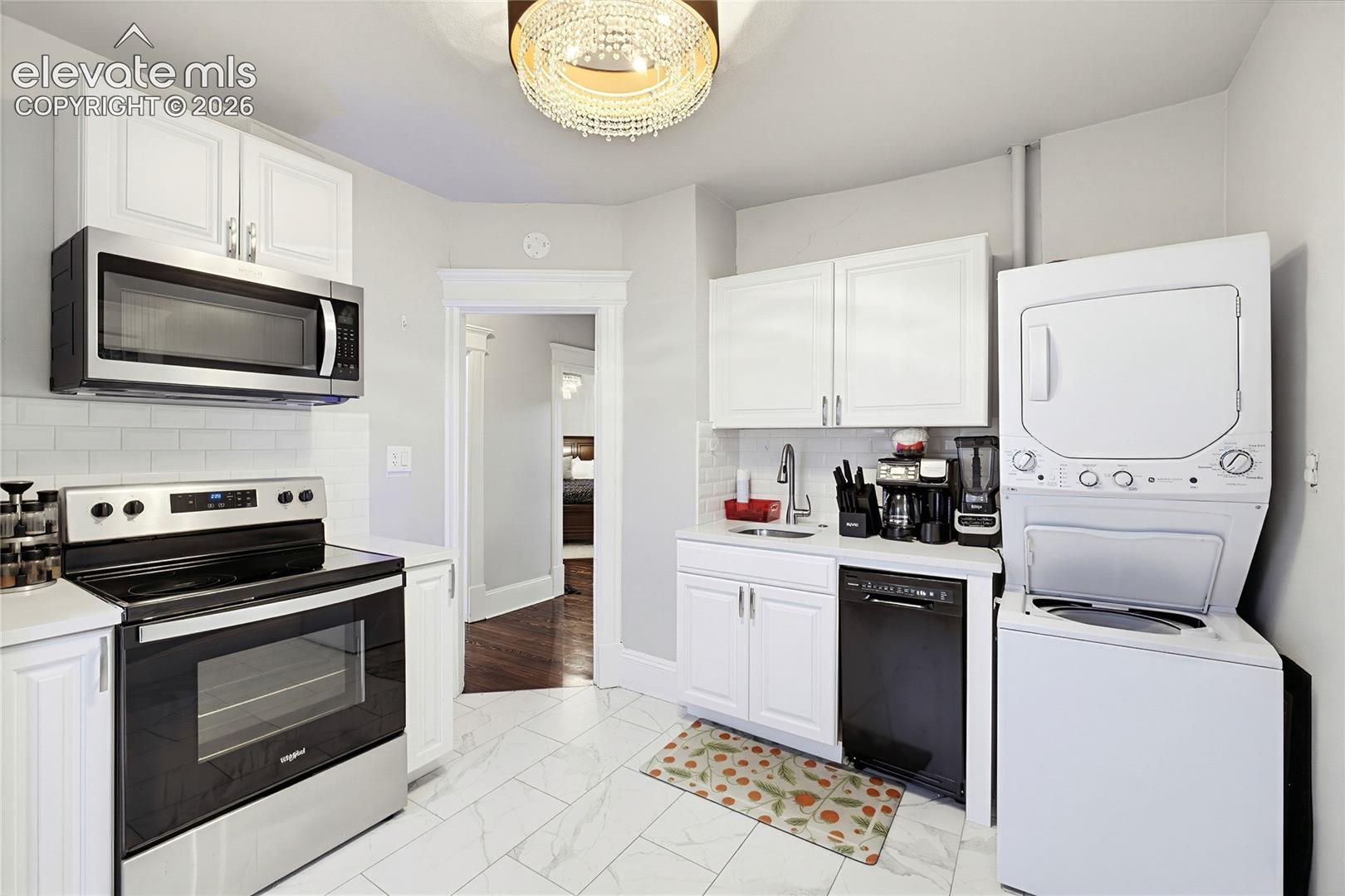 Kitchen featuring white cabinetry, stainless steel appliances, white subway tile backsplash, and light-toned tile flooring