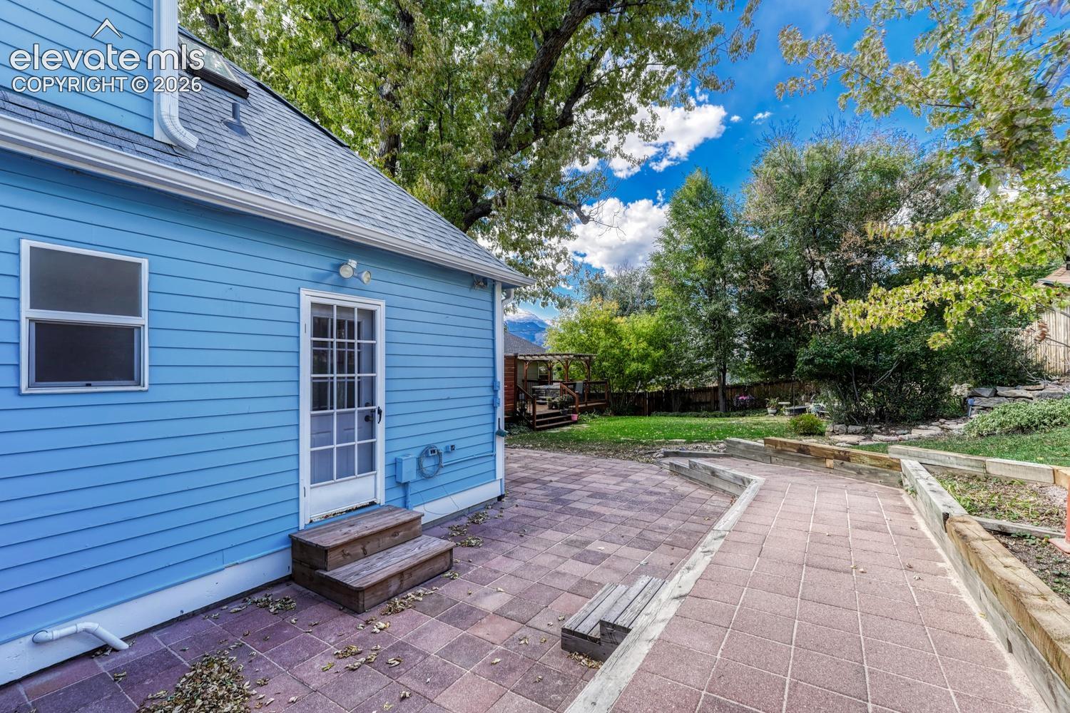 Blue horizontal siding exterior with a shingled roof, skylight, and white-framed glass pane door