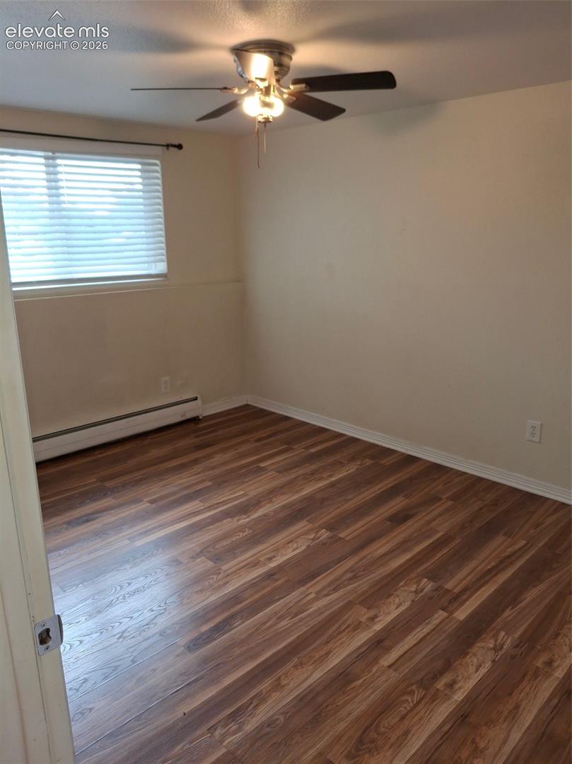 Wood-finish flooring, ceiling fan with integrated lighting, and window with horizontal blinds