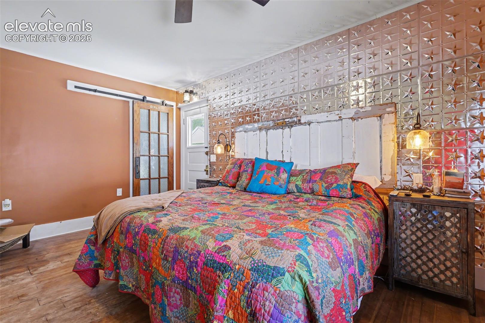 Primary bedroom with hardwood flooring and barn door