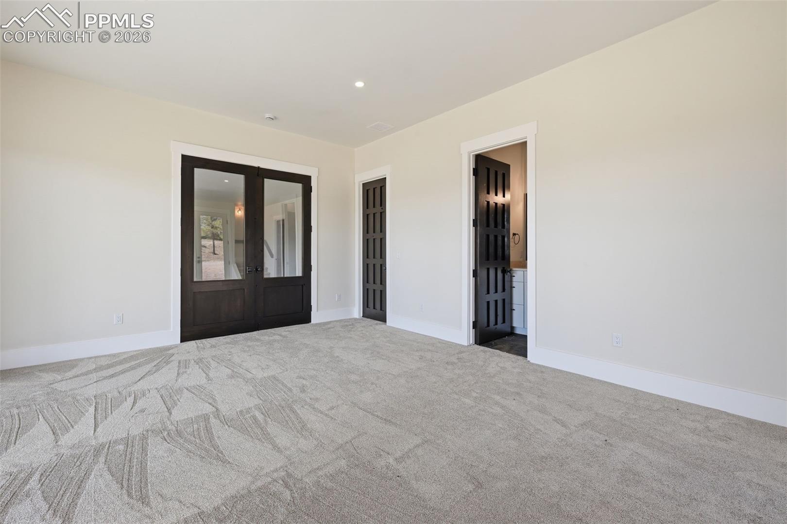 Empty room with french doors, dark colored carpet, and recessed lighting