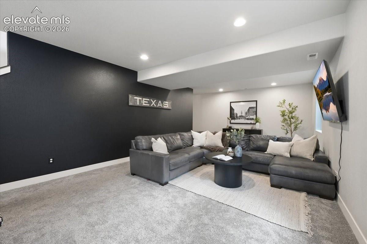 Recessed lighting, light gray carpeting, and a dark accent wall