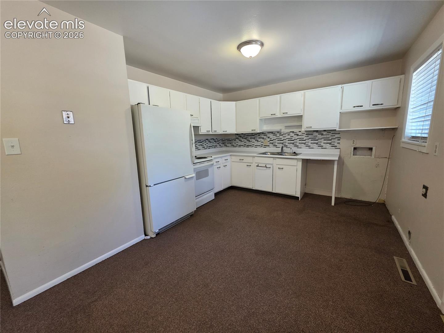 Kitchen featuring white cabinetry, white appliances, a tile backsplash, and a window with blinds