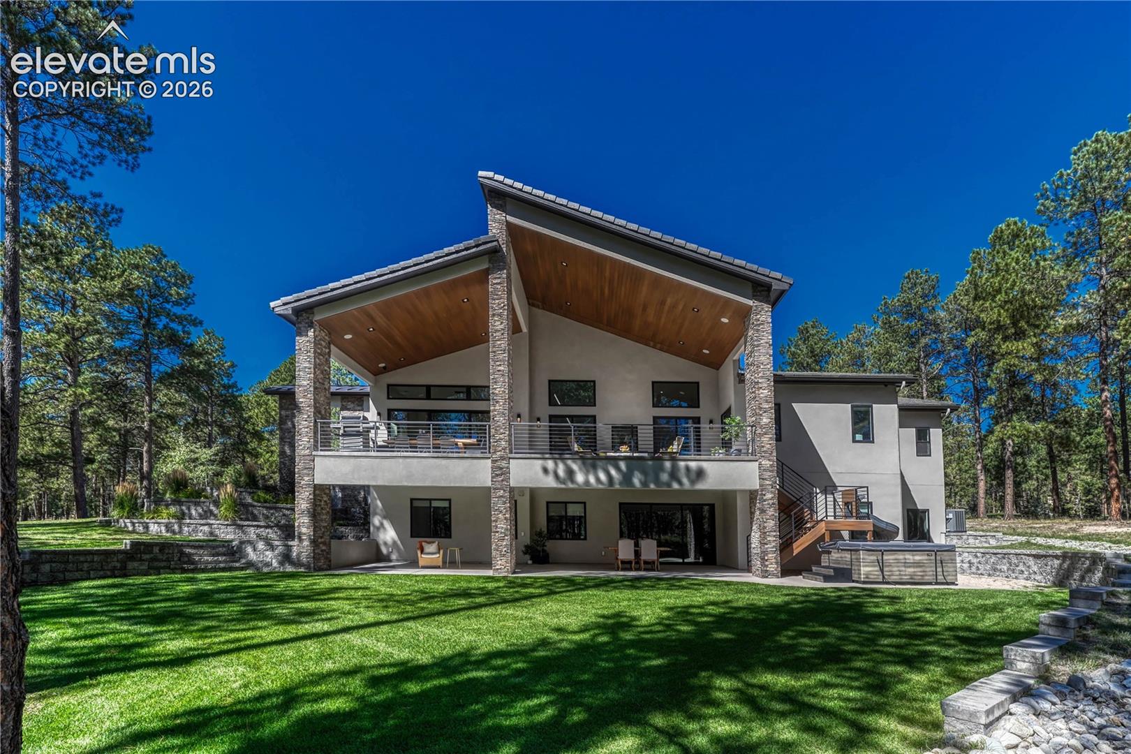 Back of property featuring stucco siding, a patio area, a lawn, and a balcony