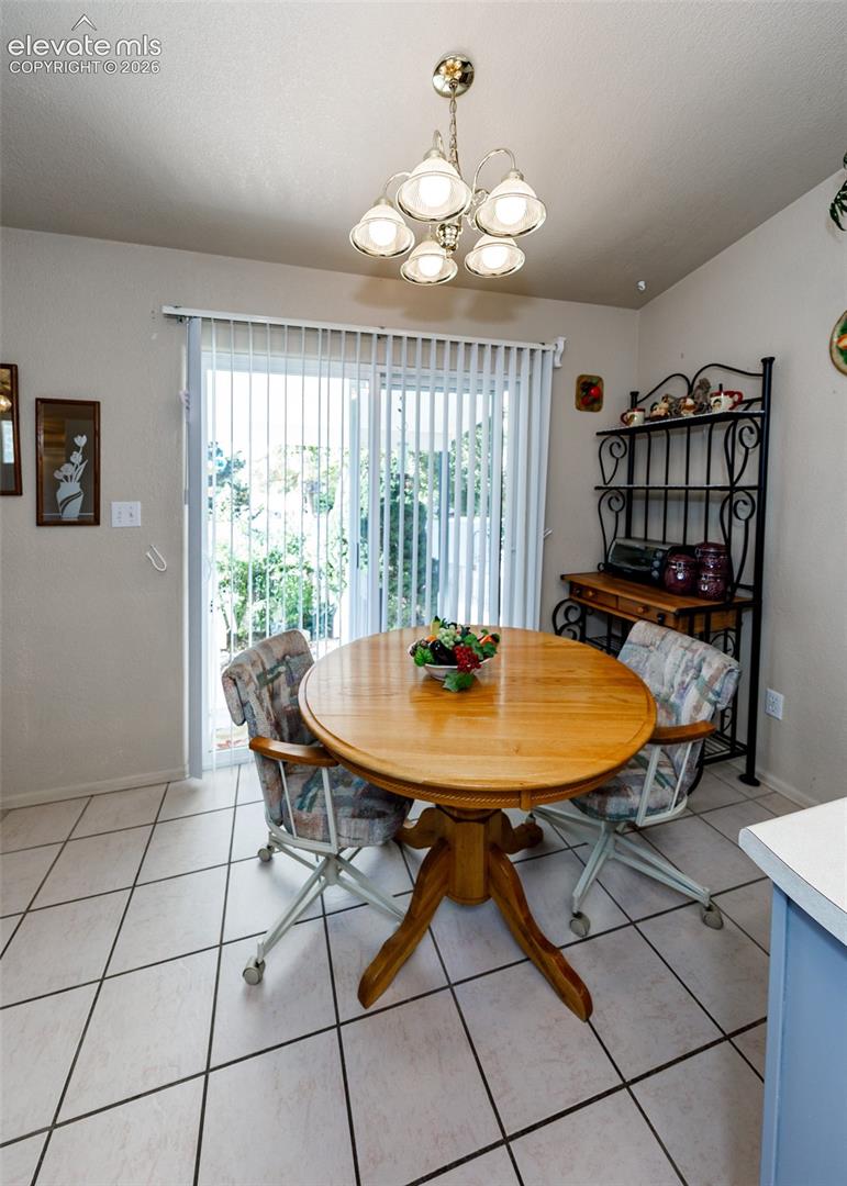 Ceramic tile flooring, five-light multi-arm chandelier, and sliding glass door with vertical blinds
