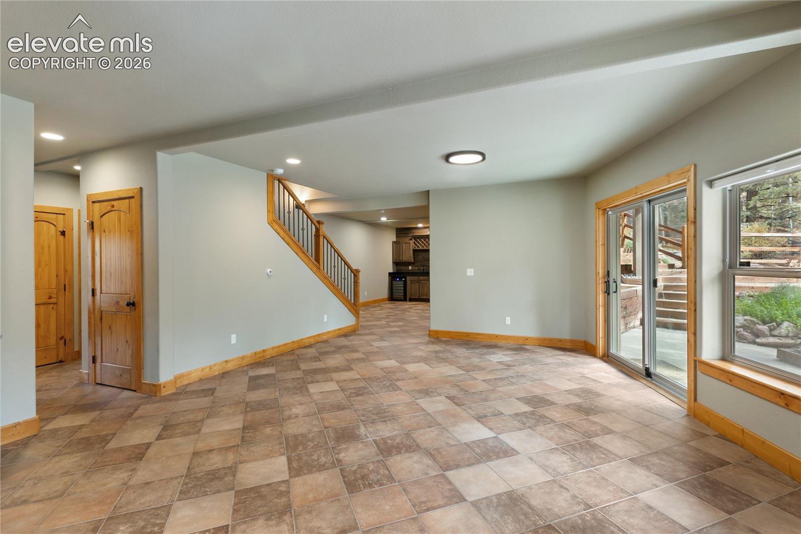 Tiled flooring, natural wood-finish interior doors and trim, staircase with metal balusters, and glass sliding doors