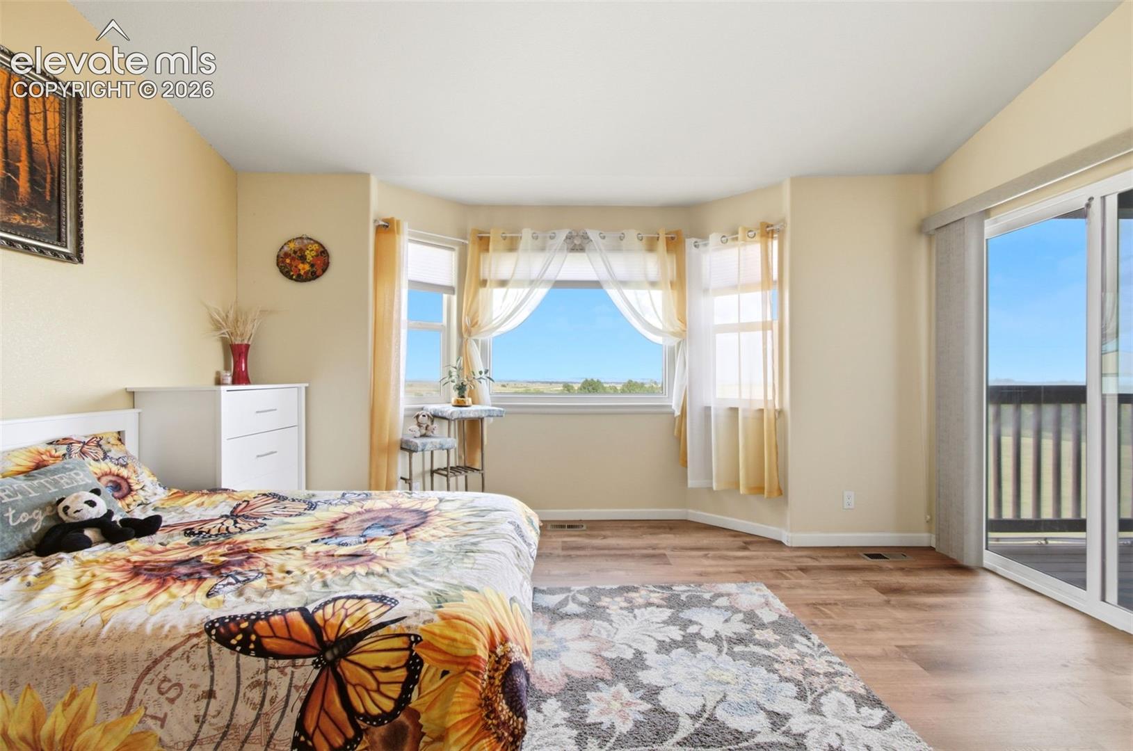 Bright, sun-filled primary bedroom featuring glass sliding door access to balcony, and ample natural light throughout
