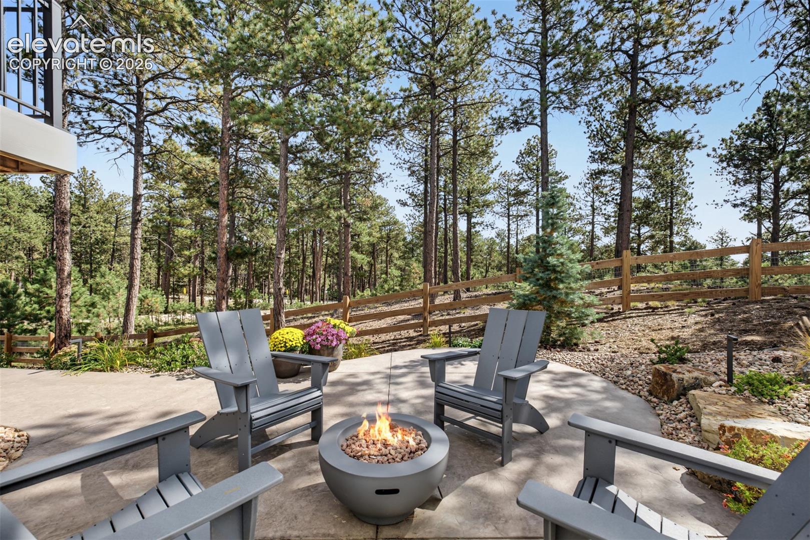Beautifully landscaped outdoor retreat featuring a custom fire pit and spacious seating area, surrounded by mature trees for a peaceful setting to relax or entertain.