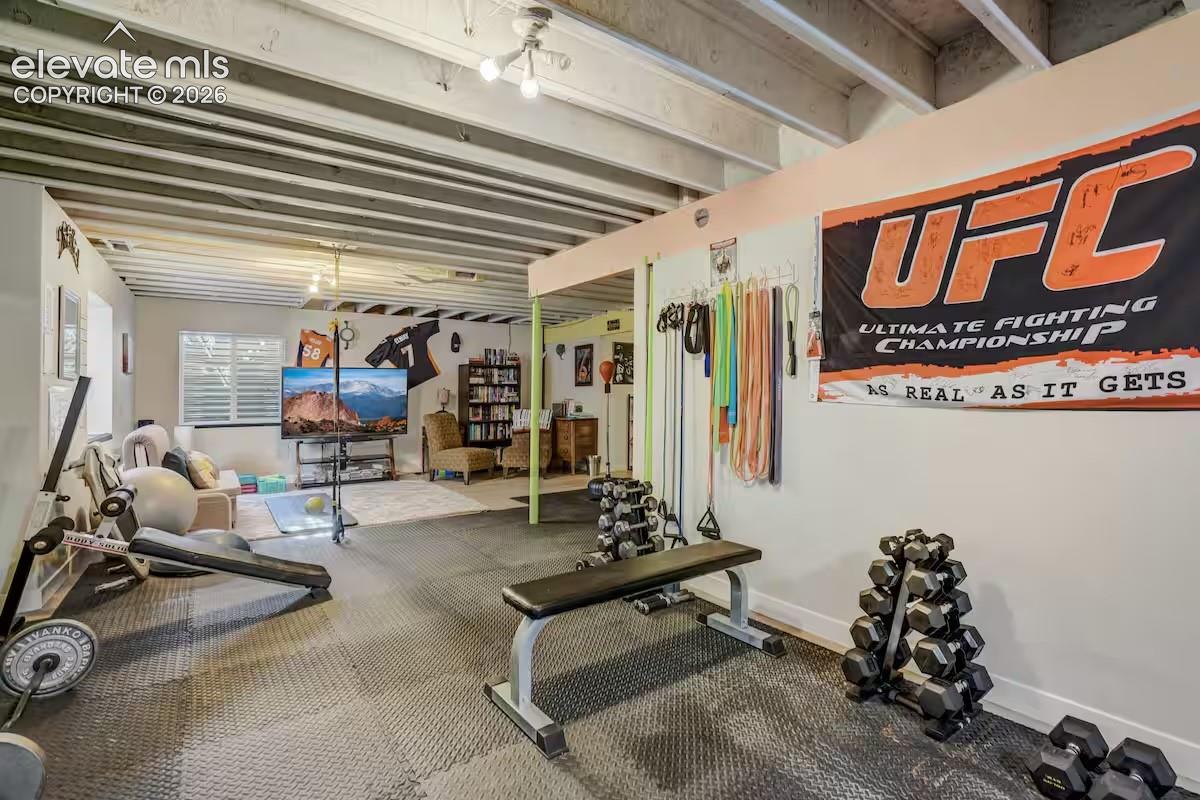 Spacious lower-level area featuring exposed ceiling joists, durable floor matting, and recessed lighting