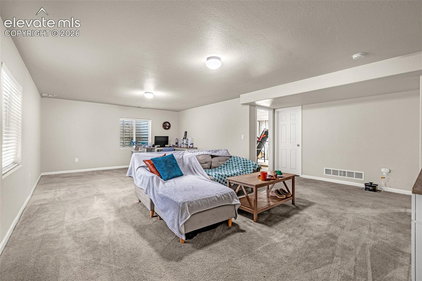 Carpeted recreation room with recessed lighting and a window featuring horizontal blinds