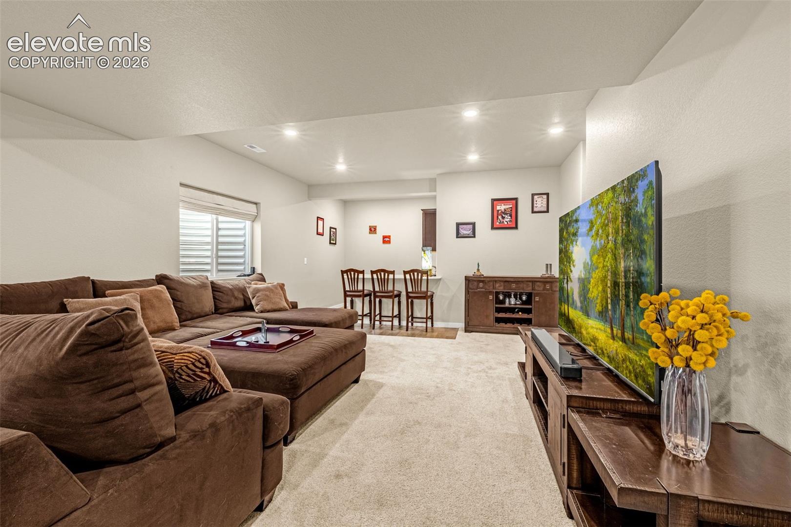 Open-concept space featuring neutral wall tones, recessed lighting, wall-to-wall carpeting, and a built-in bar counter
