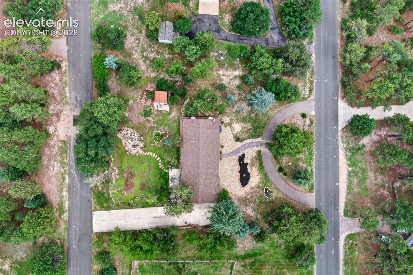 Extensive lot with mature trees, a private driveway, stone pathways, and a detached structure