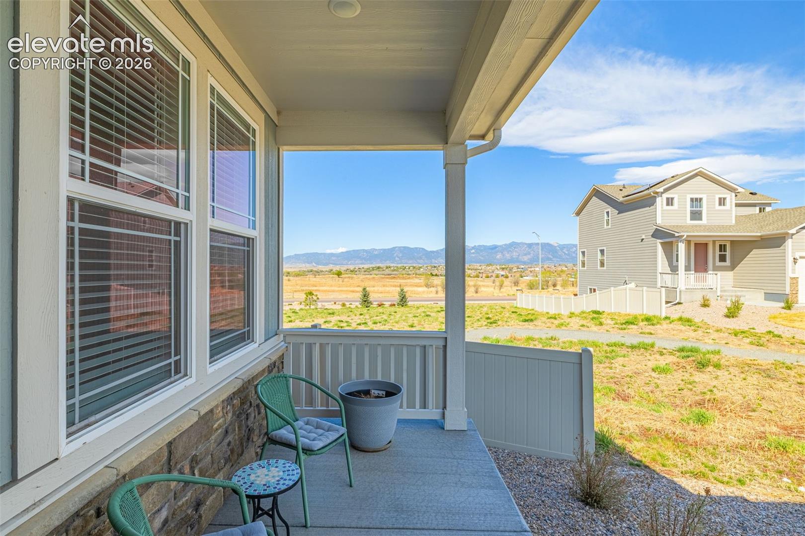 Covered porch with concrete flooring, stone veneer siding, white vinyl railing, and white-framed windows