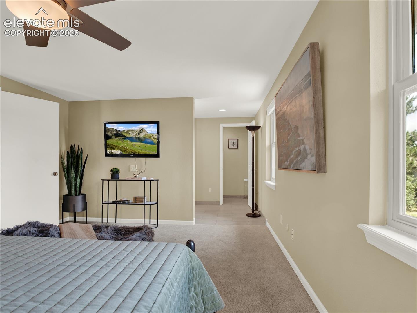 Neutral wall tones, wall-to-wall carpeting, ceiling fan with integrated lighting, and white-trim windows