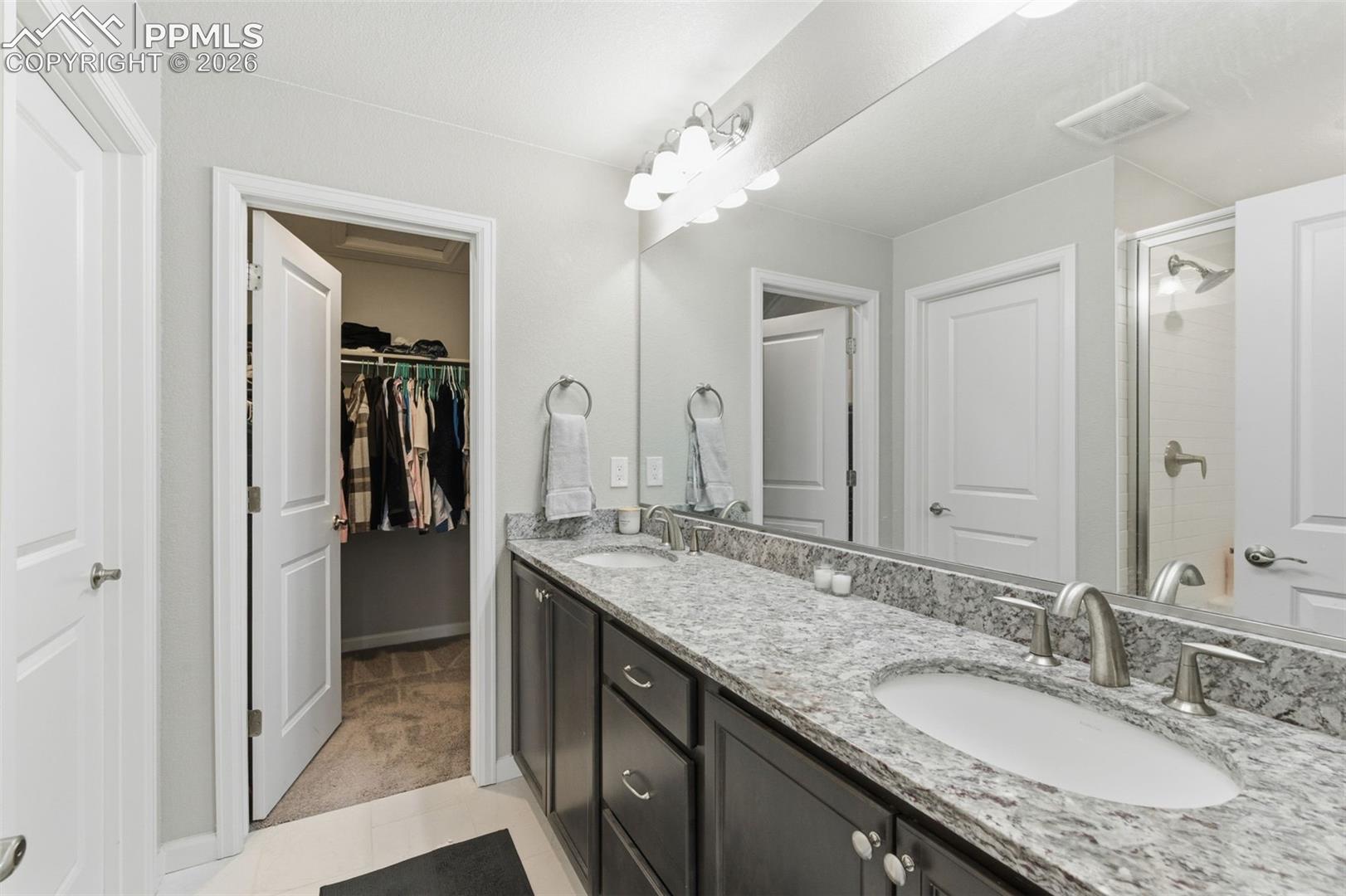 Adjoining double vanity sink, shower and walk-in closeet in 