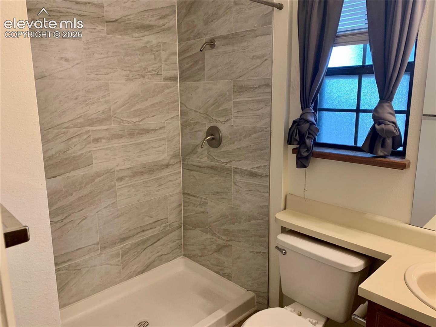 Shower with tile surround, built-in shelving, and a vanity with an integrated sink