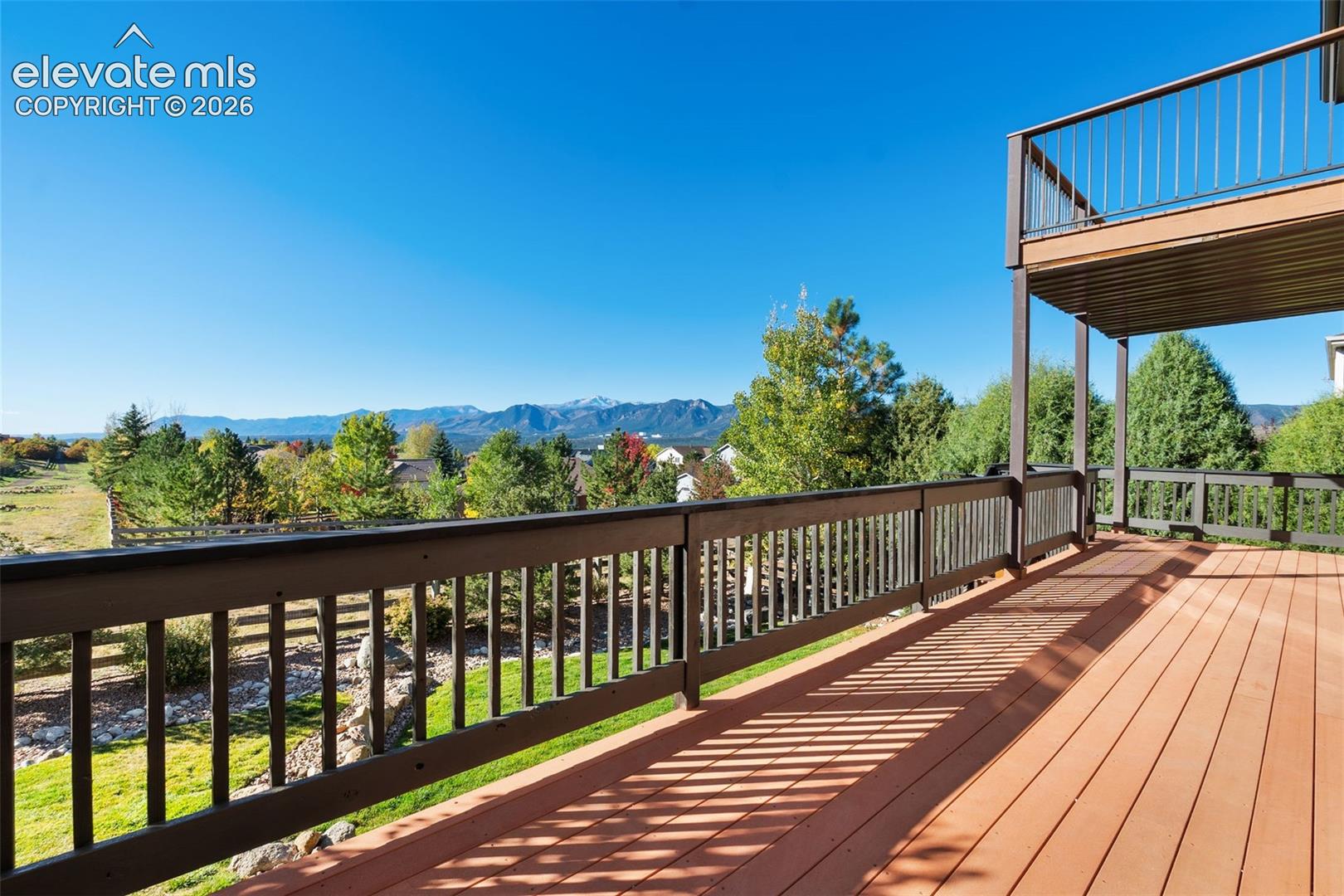 Elevated multi-level deck featuring composite wood-finish decking, dark-toned railings, and expansive mountain scenery