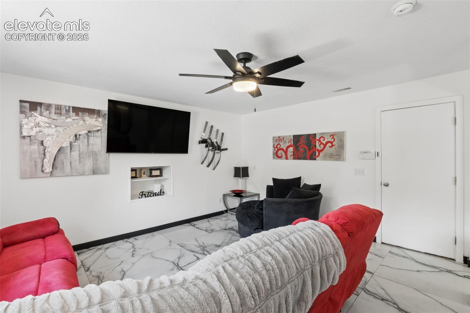 White walls, black-and-white veined flooring, recessed wall niche, and a ceiling fan with integrated lighting