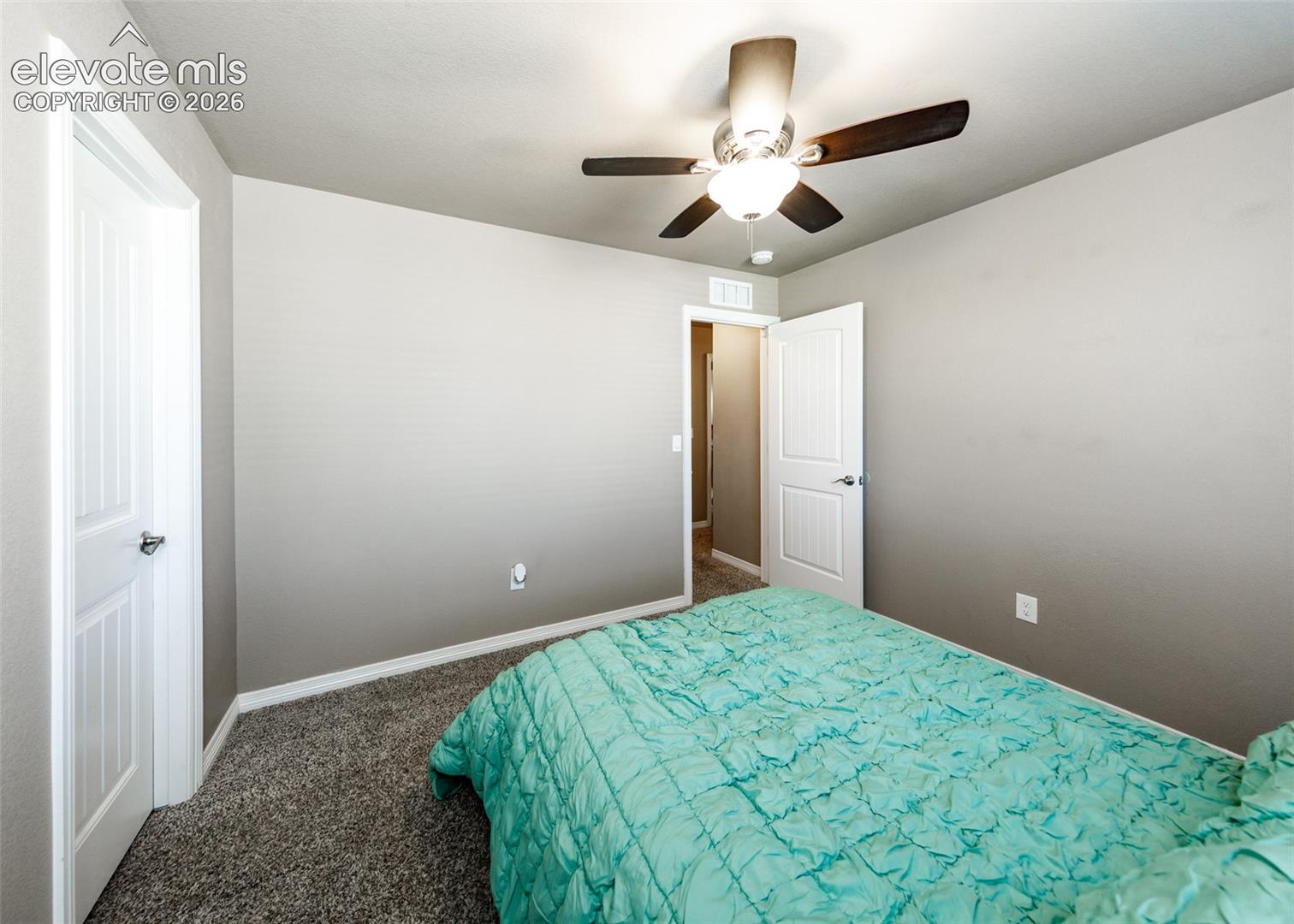 Neutral-toned walls, plush carpeting, two-panel interior doors, and a central ceiling fan with integrated lighting
