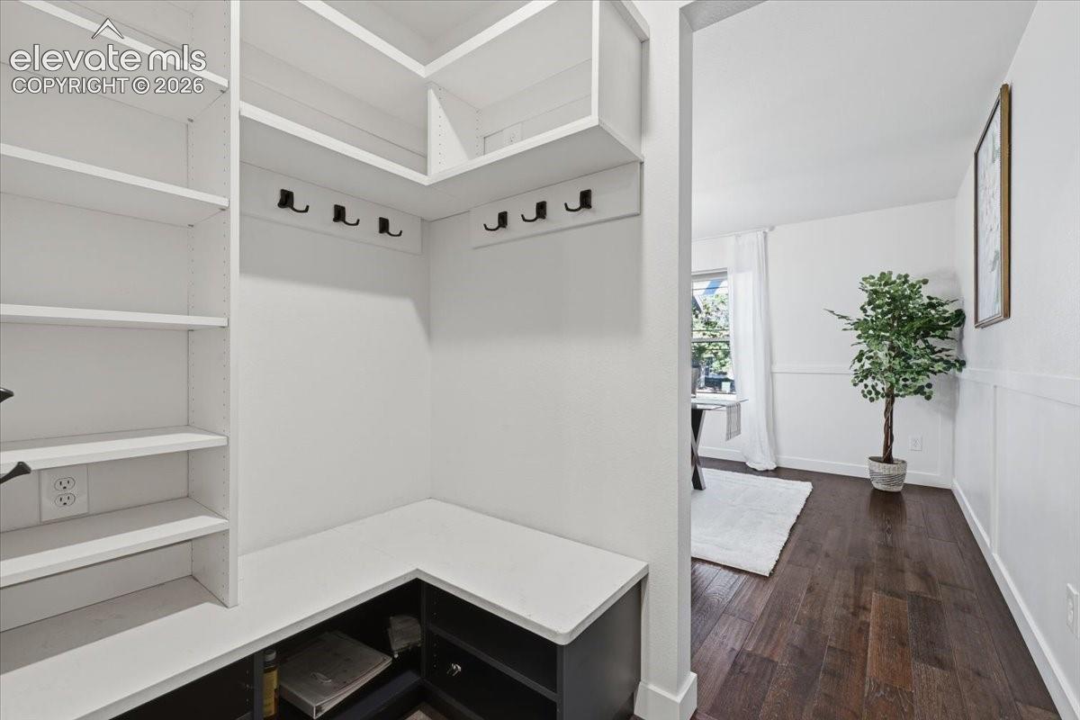 Built in shelving with integrated hooks, dark wood flooring, and bright white walls
