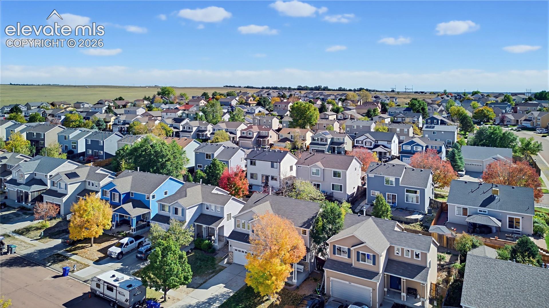 Aerial perspective of a suburban neighborhood featuring multi-story single-family residences, asphalt paved streets, concrete driveways, and mature deciduous trees