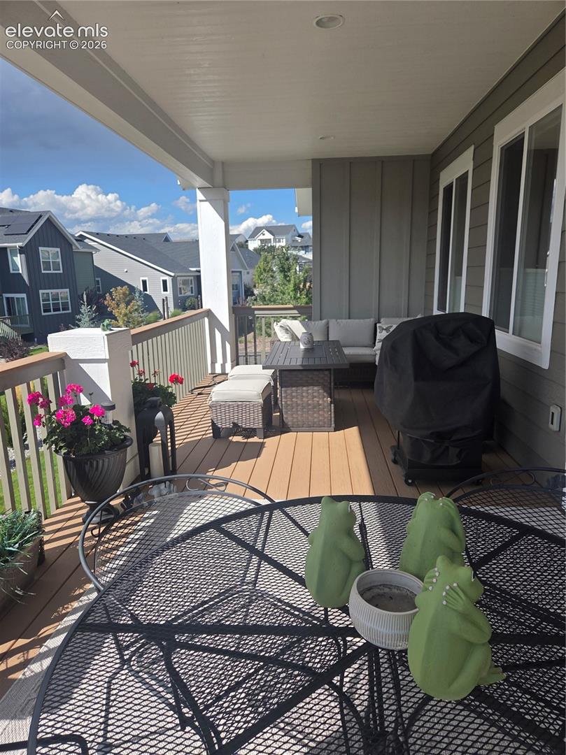 Covered outdoor balcony featuring composite decking, white railing, recessed lighting, and ample natural light
