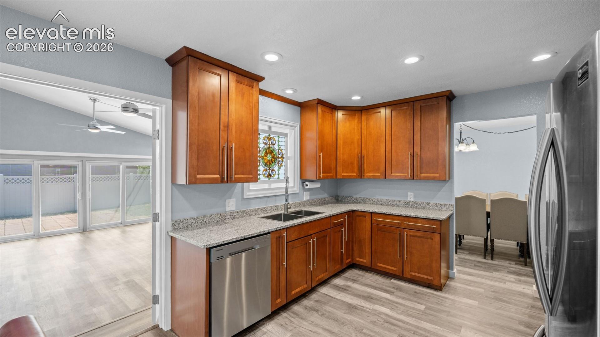 Updated kitchen featuring wood cabinetry, stainless steel appliances, granite-look countertops, and wood-finish flooring