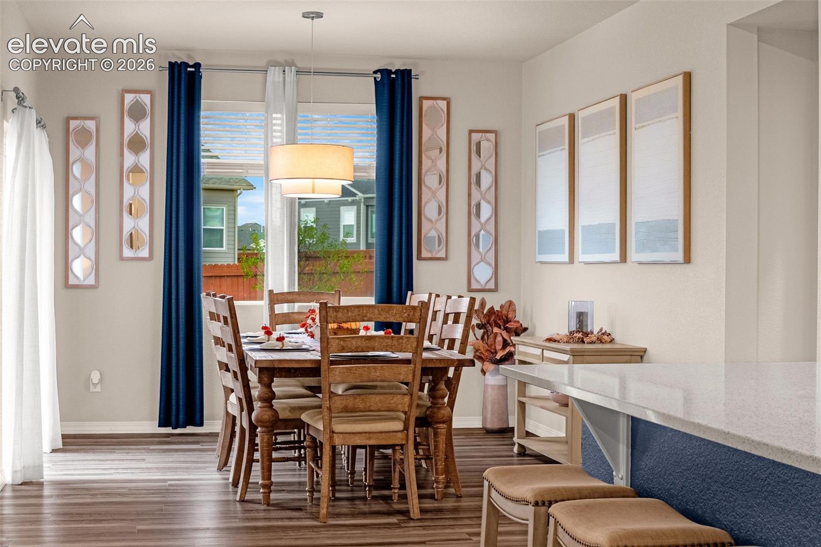 Wood-finish flooring, recessed lighting, double-paned window, drum pendant light, and a kitchen island with a light-toned countertop