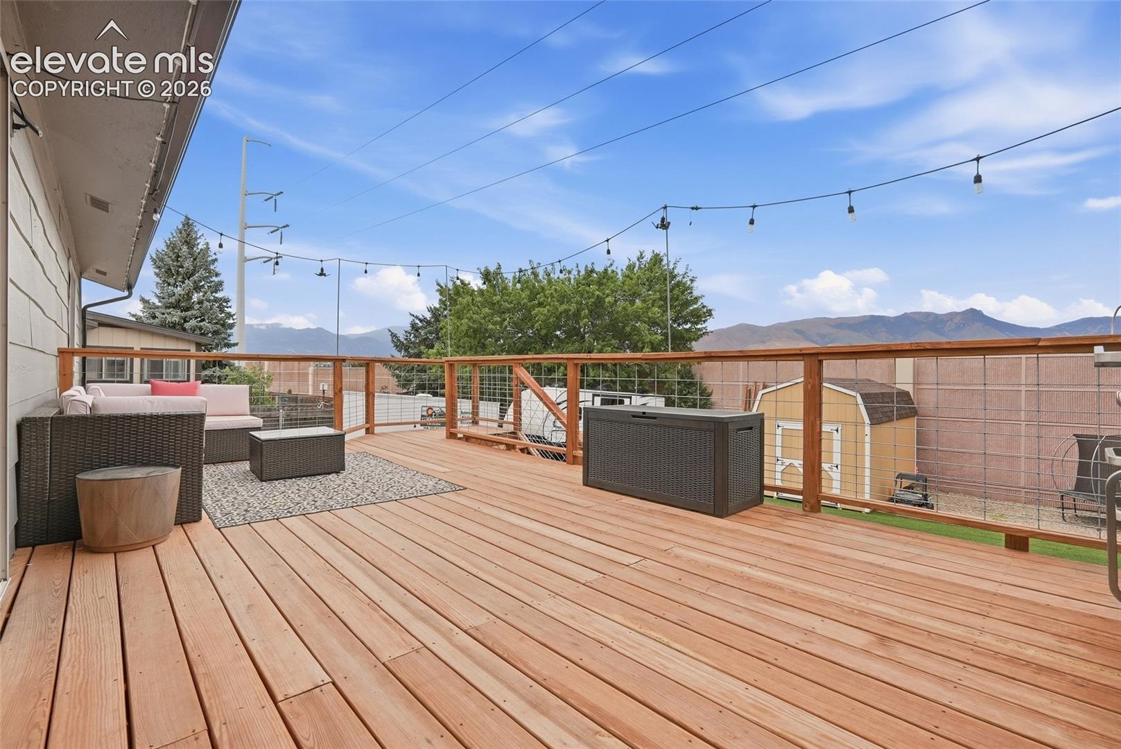 Expansive outdoor deck featuring wood flooring and a wire-mesh railing system