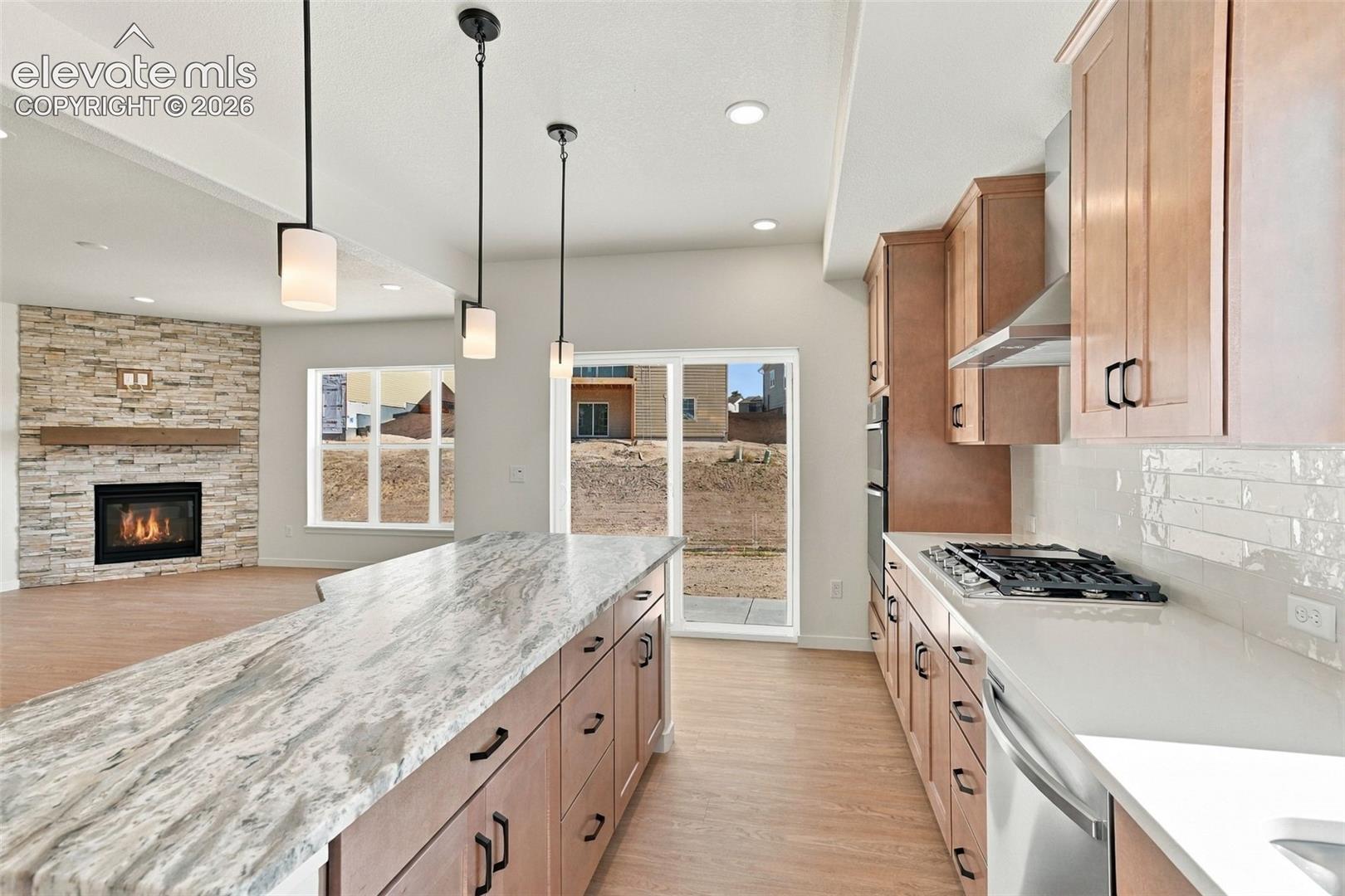 The Kitchen features stainless steel appliances, light maple cabinets with pecan stain, a large kitchen island with quartz countertop, and LVP flooring.