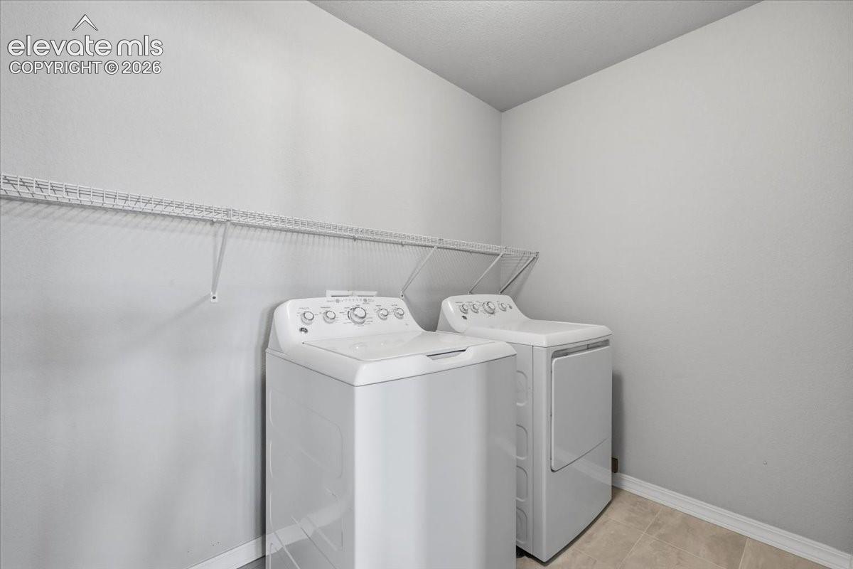 Laundry space featuring neutral wall tones, tile flooring, and integrated white wire shelving