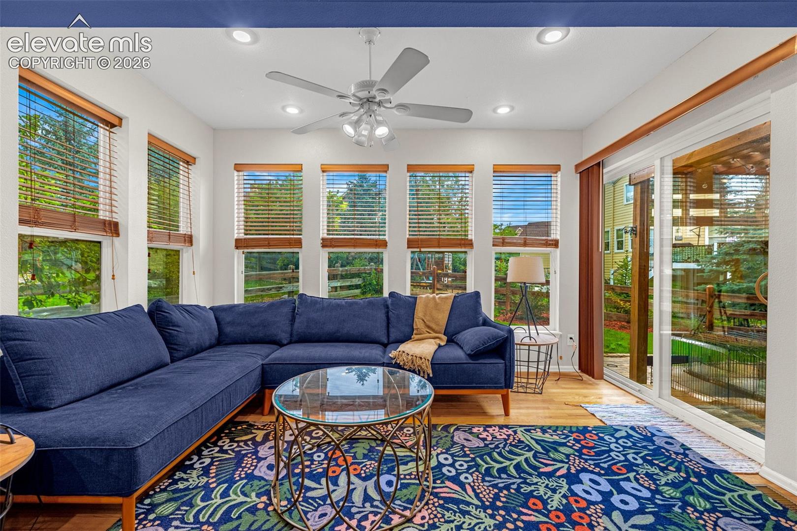 Recessed lighting, wood-finish flooring, multiple windows with blinds, ceiling fan, and sliding glass door