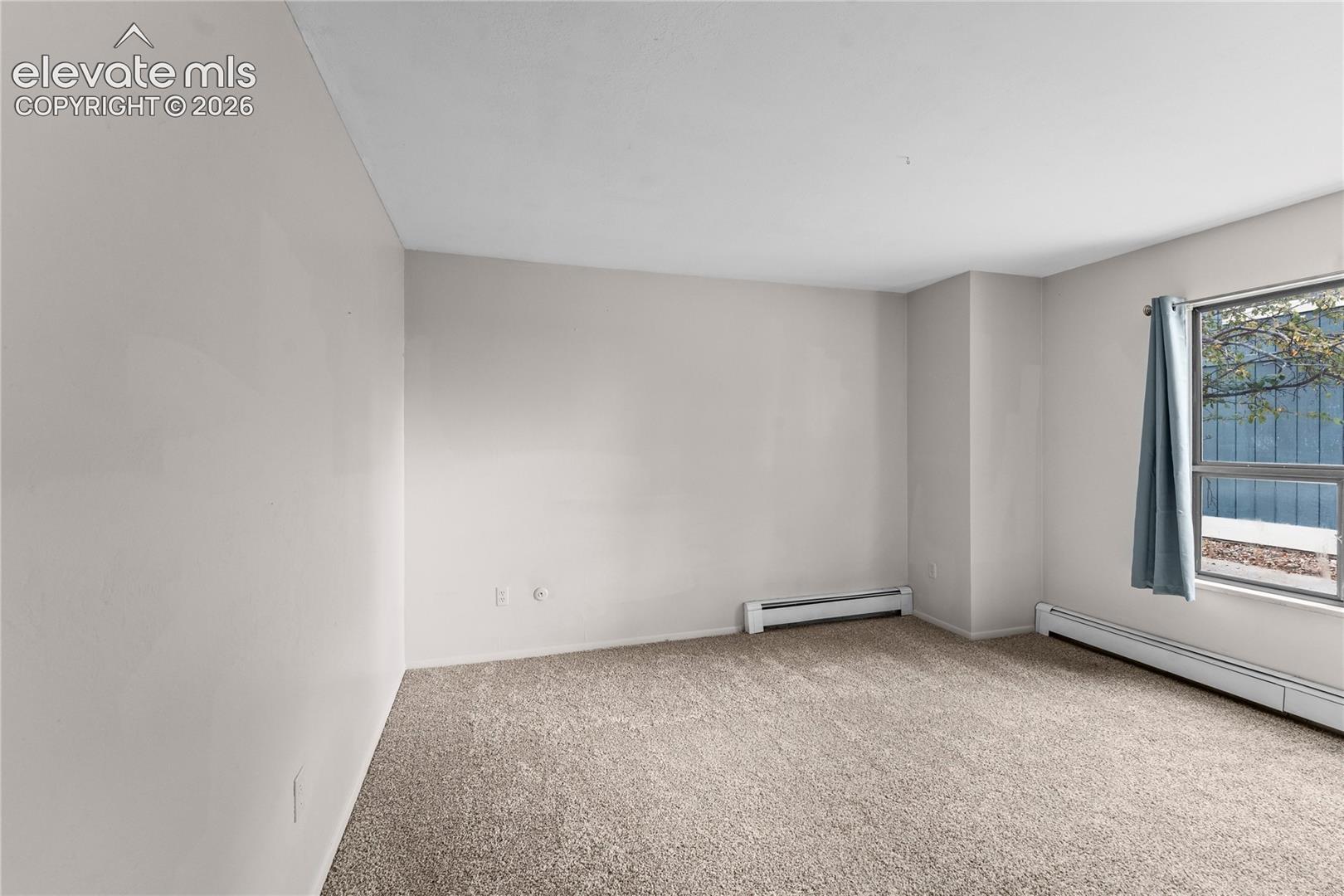 Neutral-toned interior space featuring wall-to-wall carpeting and a multi-pane window