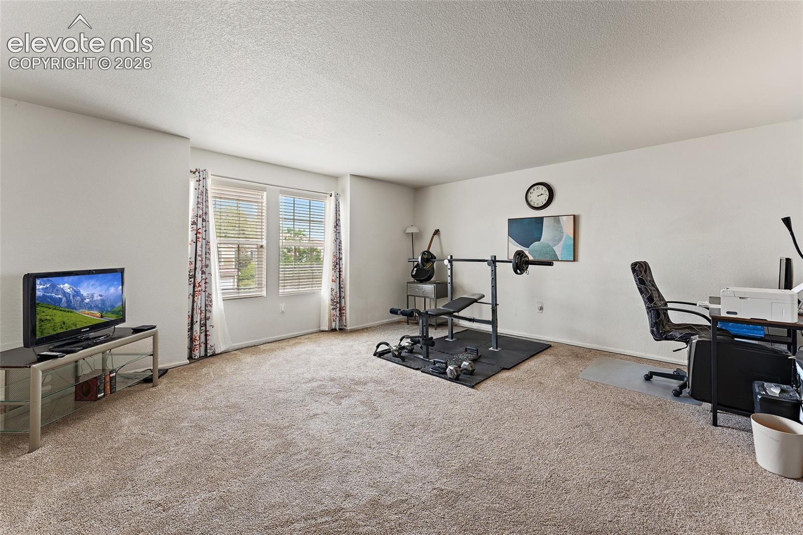 Spacious room featuring neutral carpeting, high ceilings, and double-pane windows