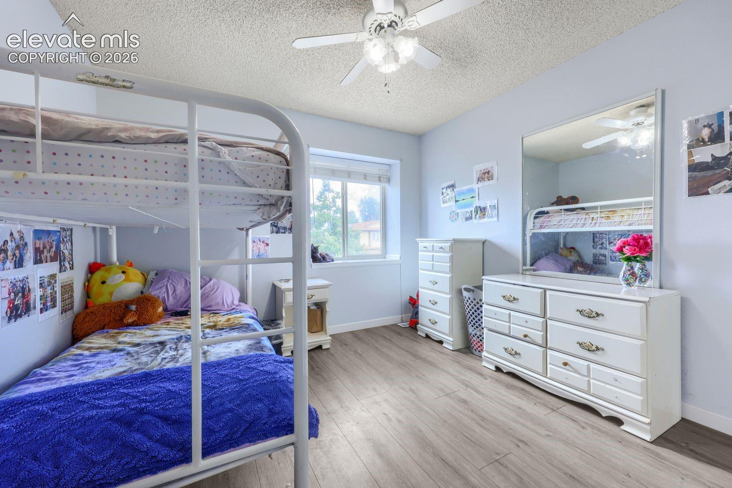 Wood-finish flooring, ceiling fan, and window providing natural light