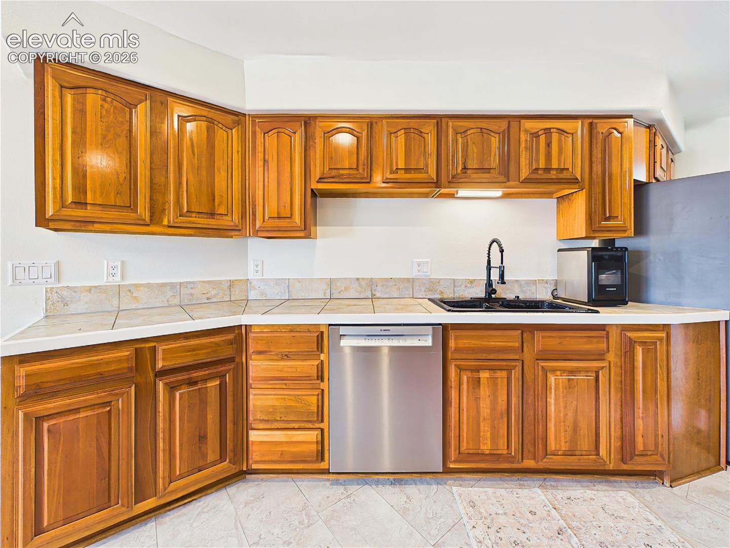 Rich wood cabinetry and extensive countertop space provide ample storage and functionality throughout this inviting kitchen.