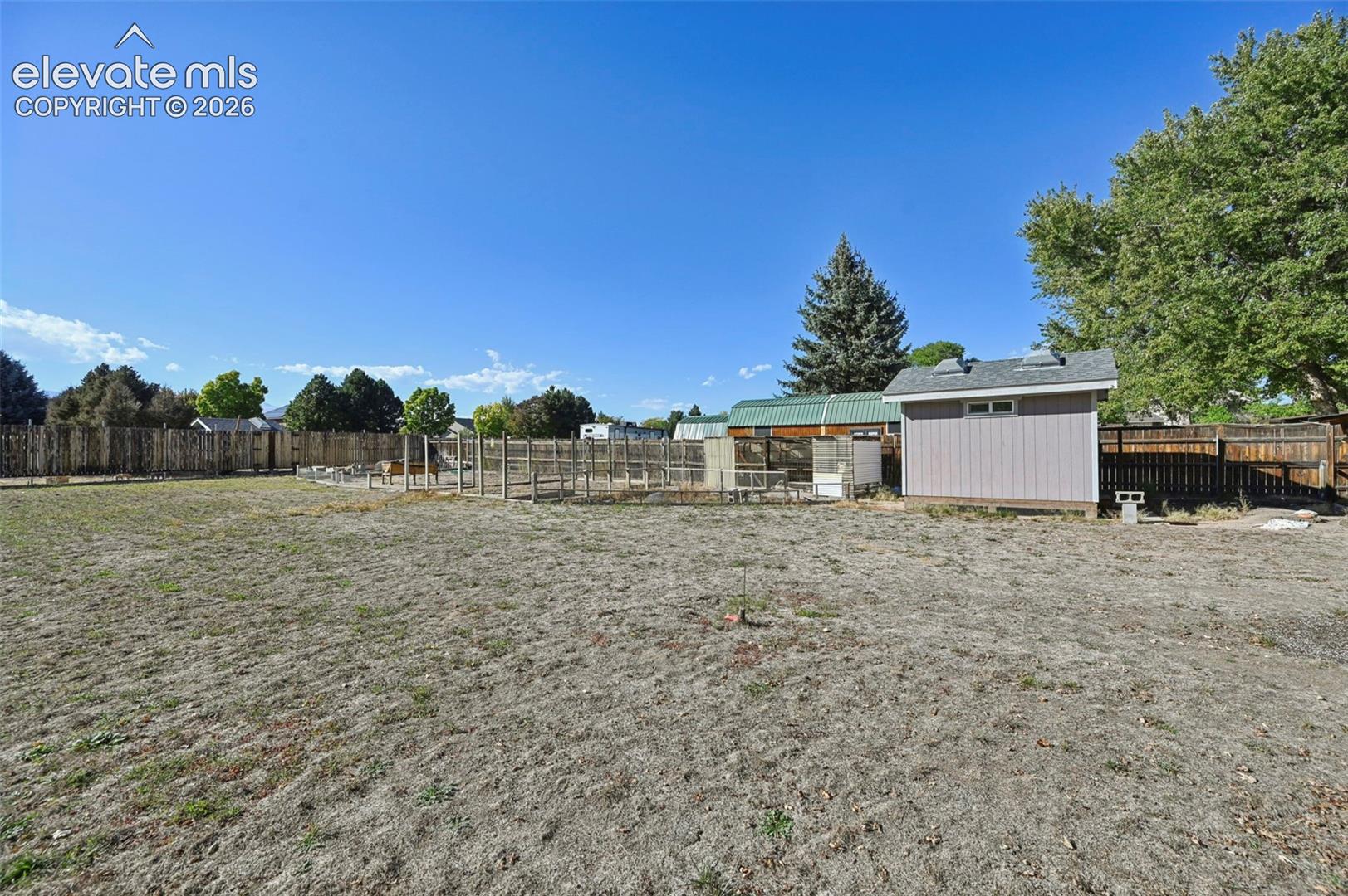 Expansive yard space featuring a detached storage shed, wood fencing, and mature trees
