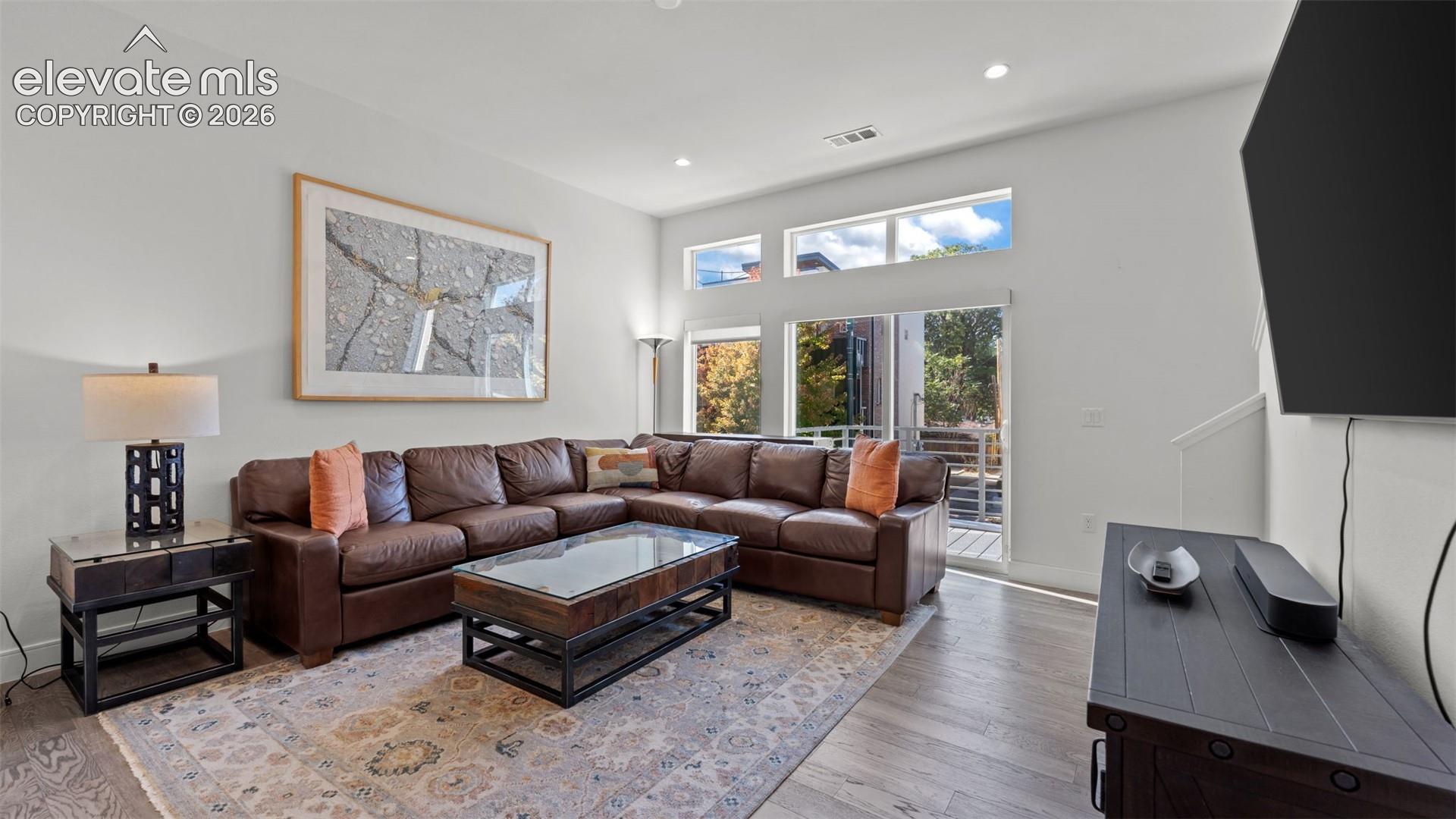 High ceilings featuring clerestory windows, wood-finish flooring, and recessed lighting